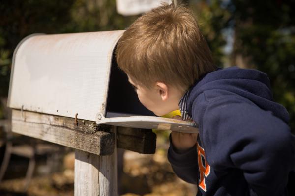 child looking into a mailbox longingly 